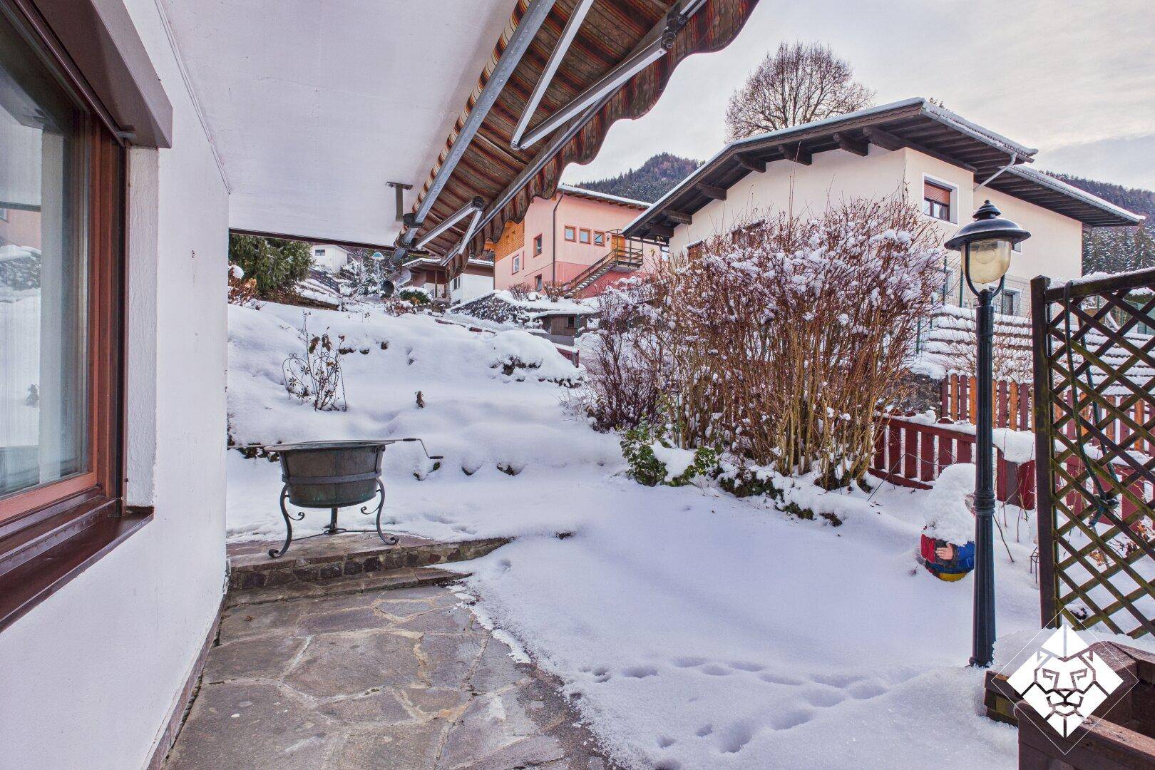 Kleiner Gartenbereich mit Steinplatten und schneebedeckten Büschen, ideal für den Winter.