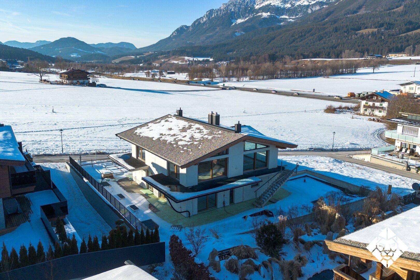 Modernes Einfamilienhaus in verschneiter Landschaft mit weitem Blick auf die Berge.