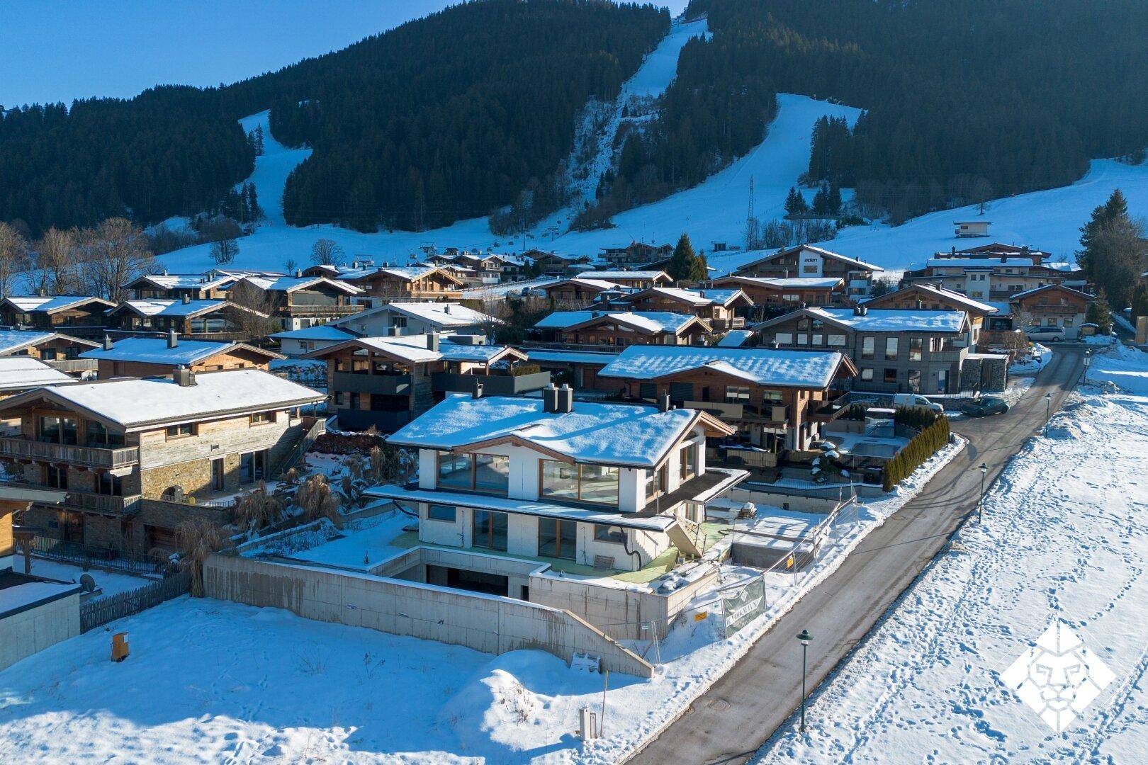 Neues Einfamilienhaus in einer Wohnsiedlung mit verschneiten Dächern und Bergblick.