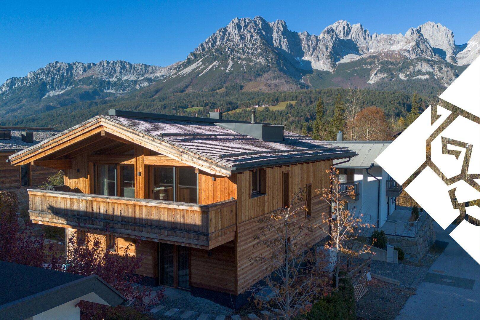 Modernes Holzchalet mit Balkon und beeindruckendem Bergblick in sonniger alpiner Umgebung.