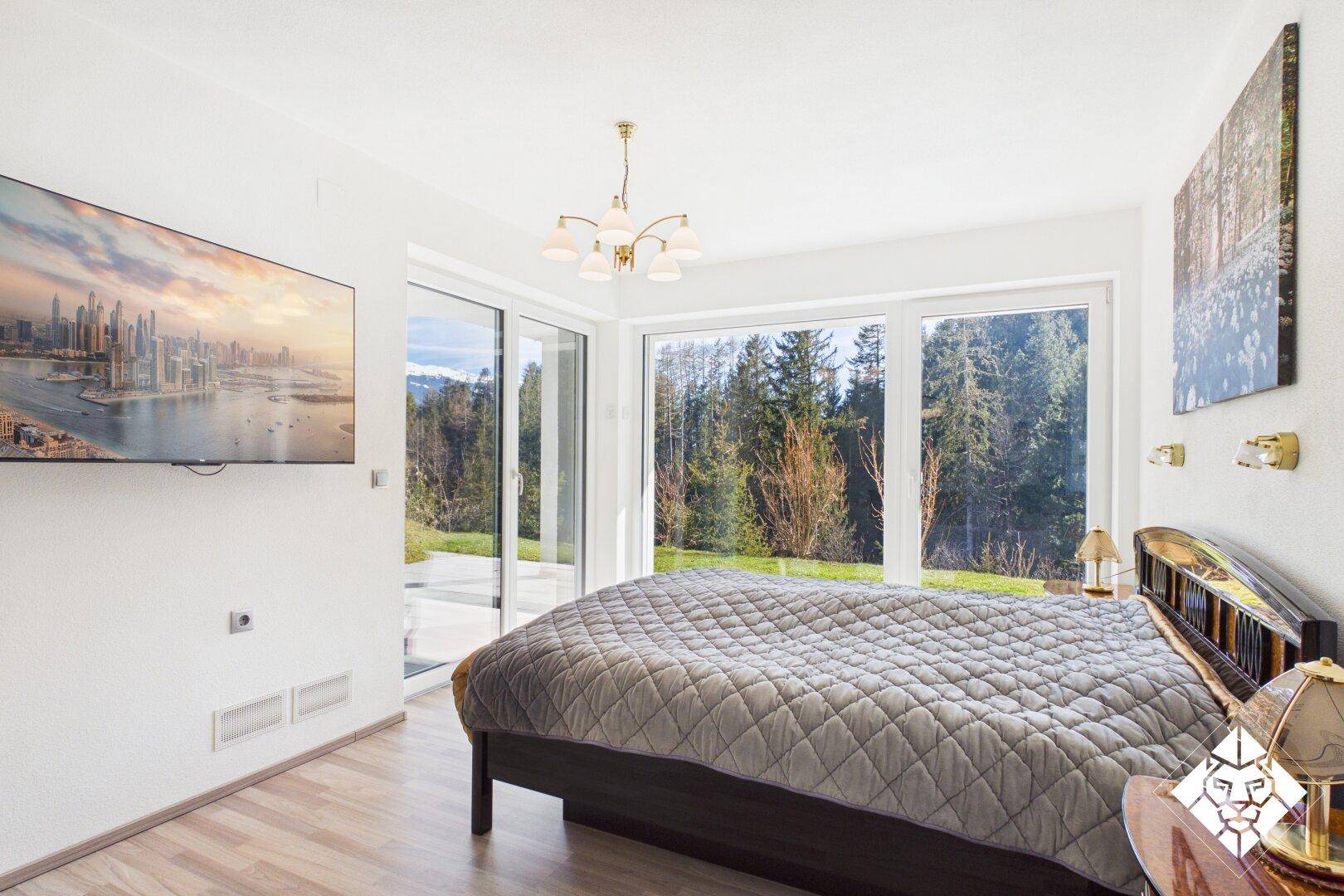 Geräumiges Schlafzimmer mit großem Bett, Fernseher und Panoramafenstern mit Bergblick.