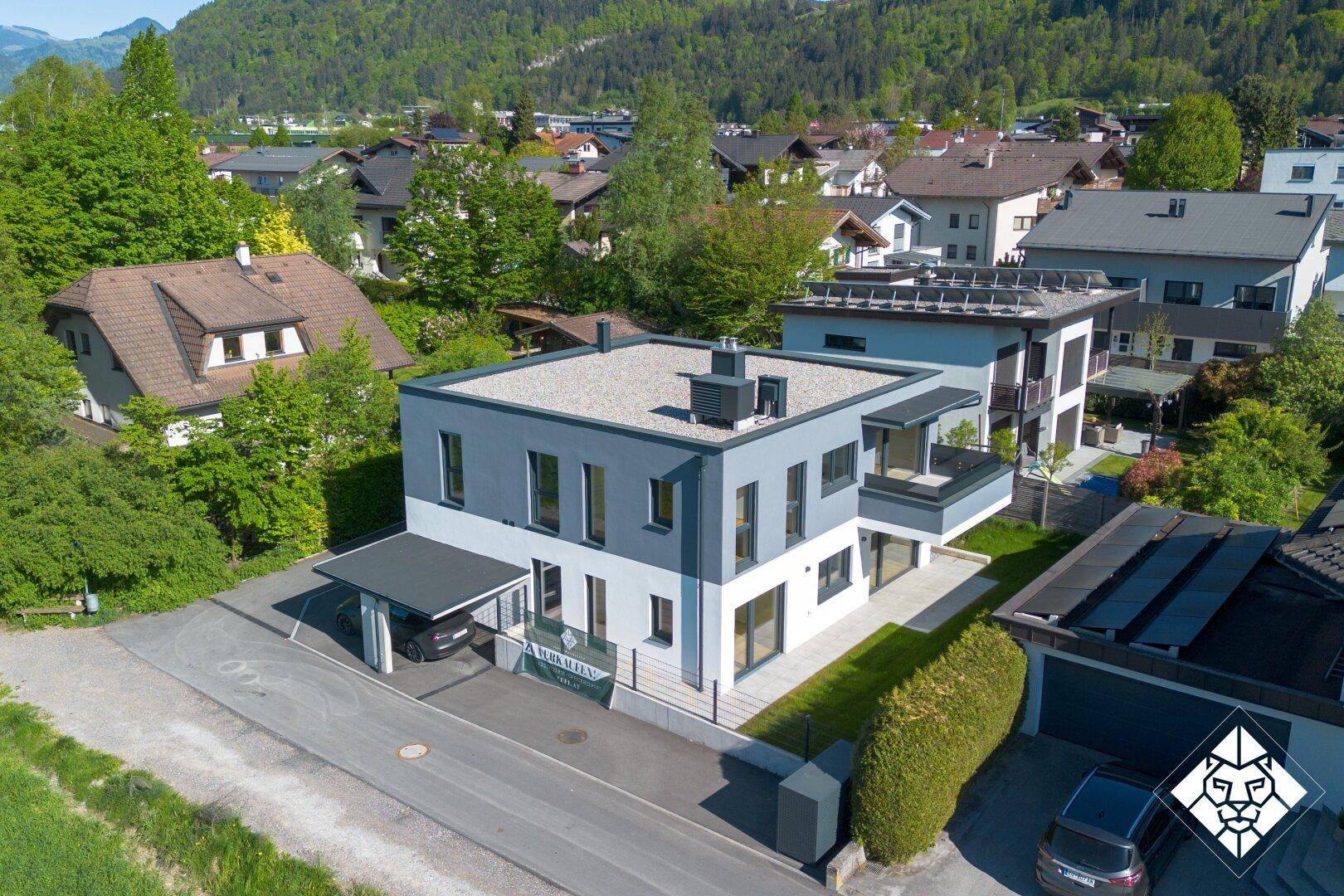 Luftaufnahme des modernen Hauses in einer Wohnsiedlung mit Blick auf die umliegende Bergwelt.