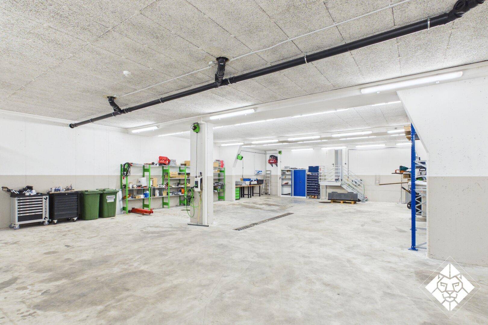 Geräumige Garage oder Werkstatt mit Betonboden und viel Stauraum, ideal für Fahrzeuge und Hobbys.