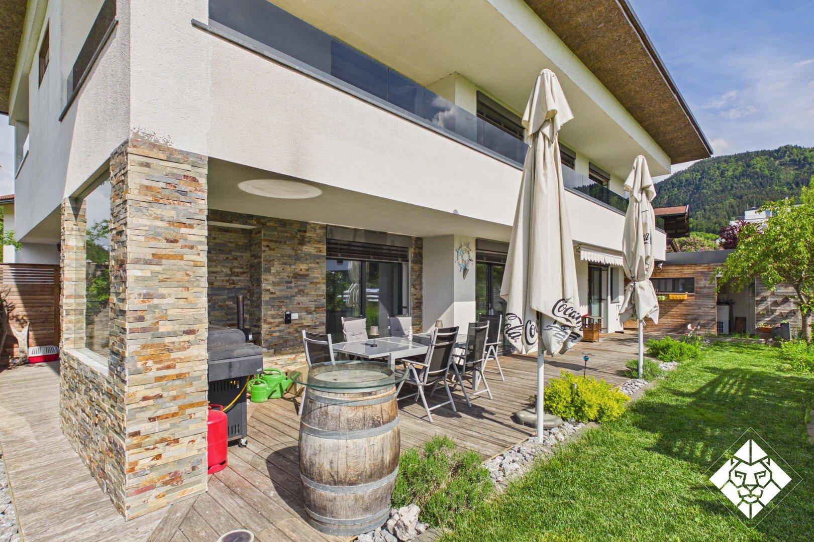Geräumige Terrasse mit Grillbereich, Garten und Blick auf die grüne Landschaft.