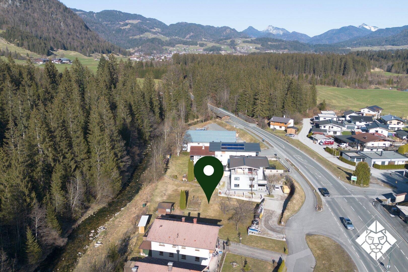 Luftaufnahme einer Wohngegend mit Wald, Straße und einem markierten Standort in ländlicher Umgebung.