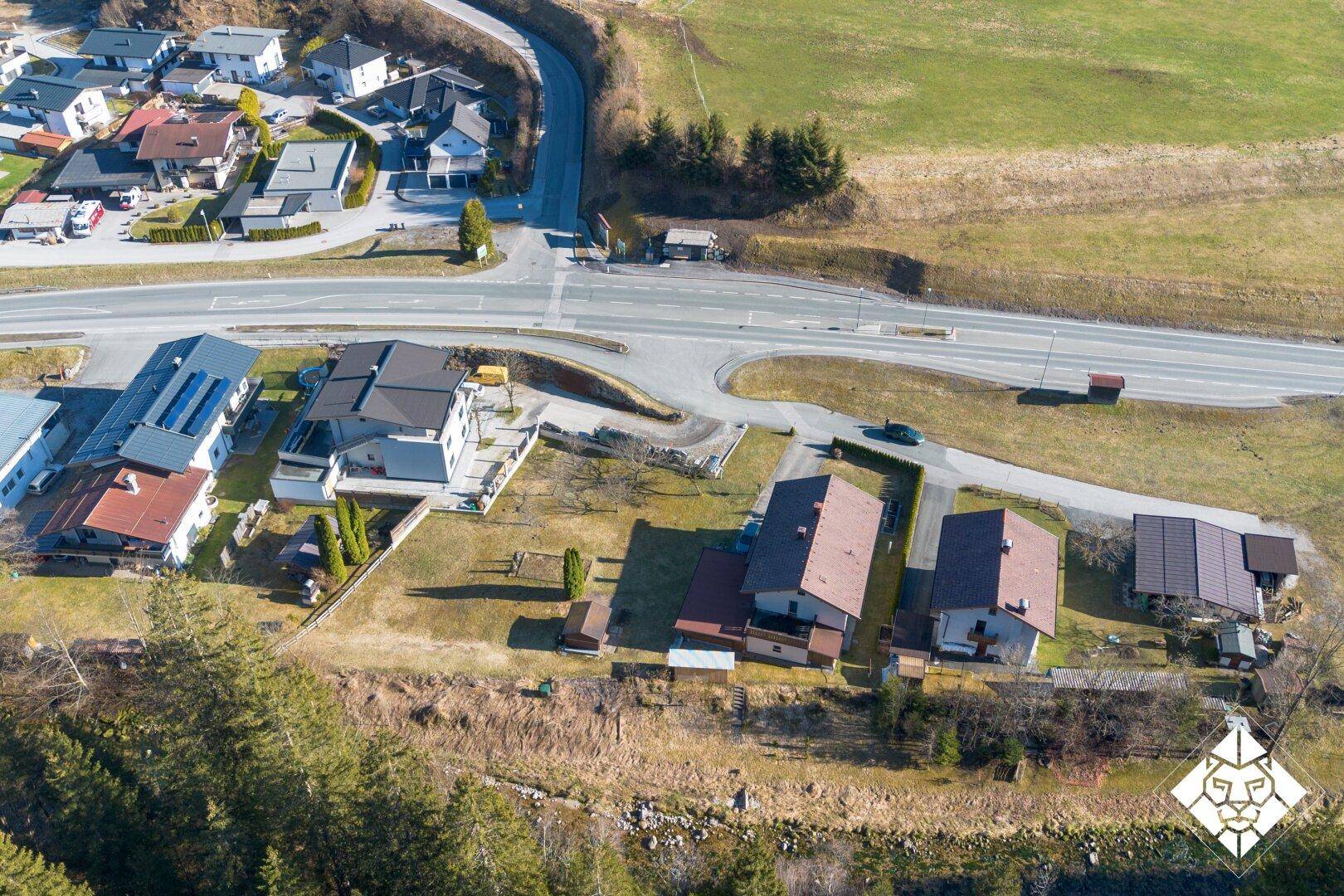 Panoramablick aus der Luft auf eine ländliche Siedlung mit Straßen, Feldern und angrenzendem Waldgebiet.