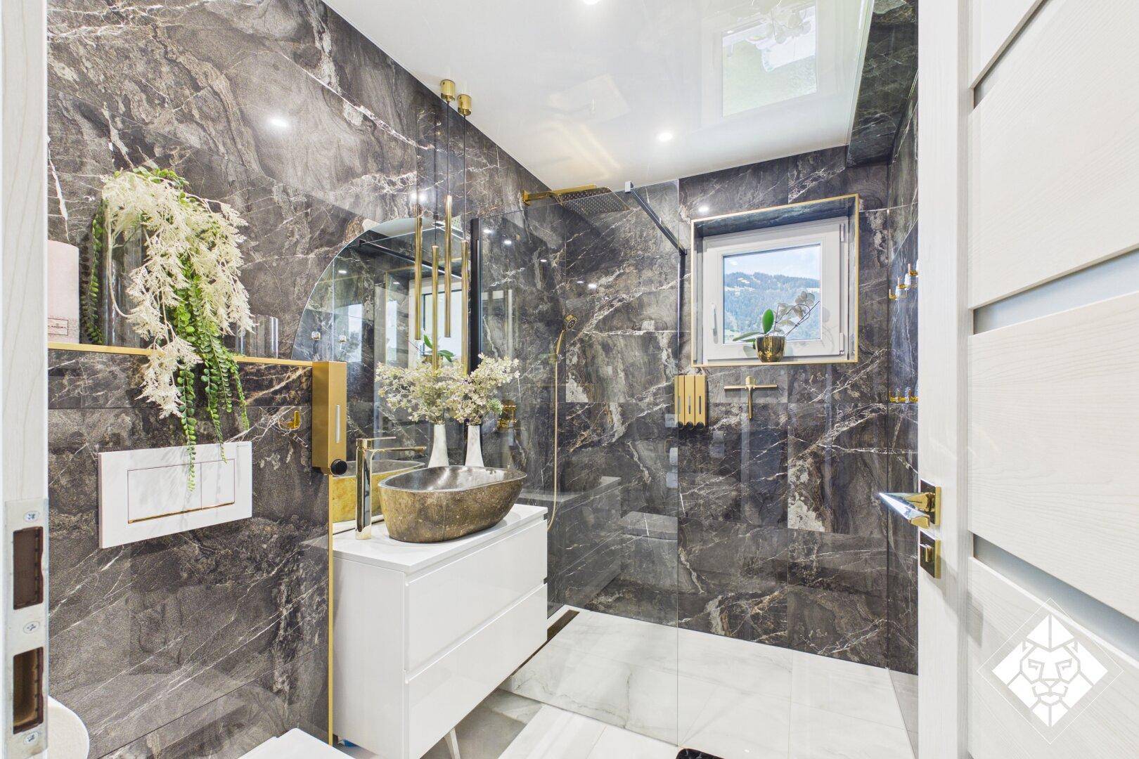 Luxuriöses Badezimmer mit dunklen Marmorfliesen, moderner Dusche und Fenster.