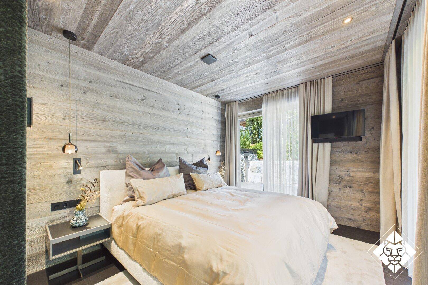Gemütliches Schlafzimmer mit Holzwänden, Holzboden und Blick ins Grüne.