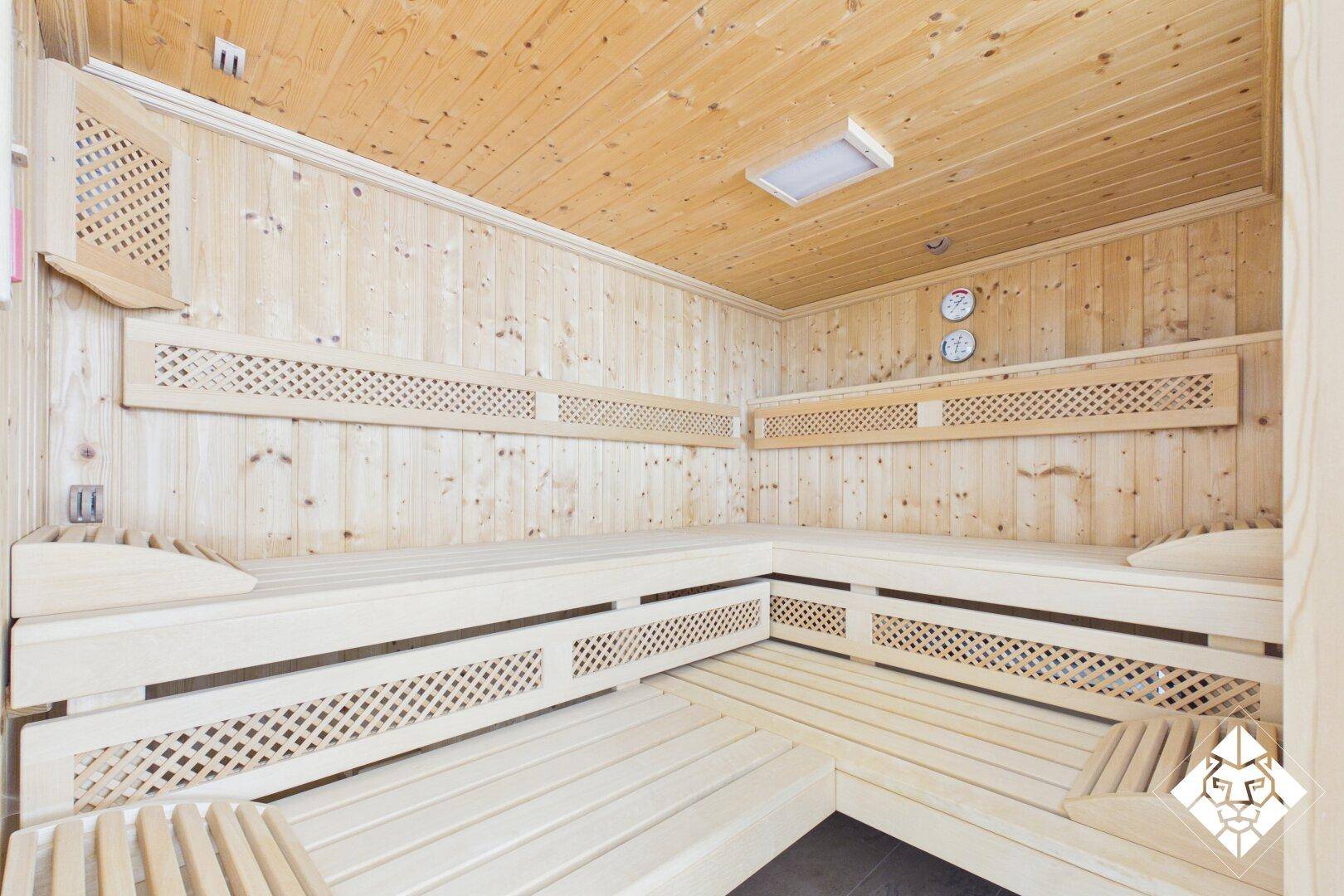 Traditionelle Holzsauna mit mehreren Bänken und angenehmer Beleuchtung für Entspannung.