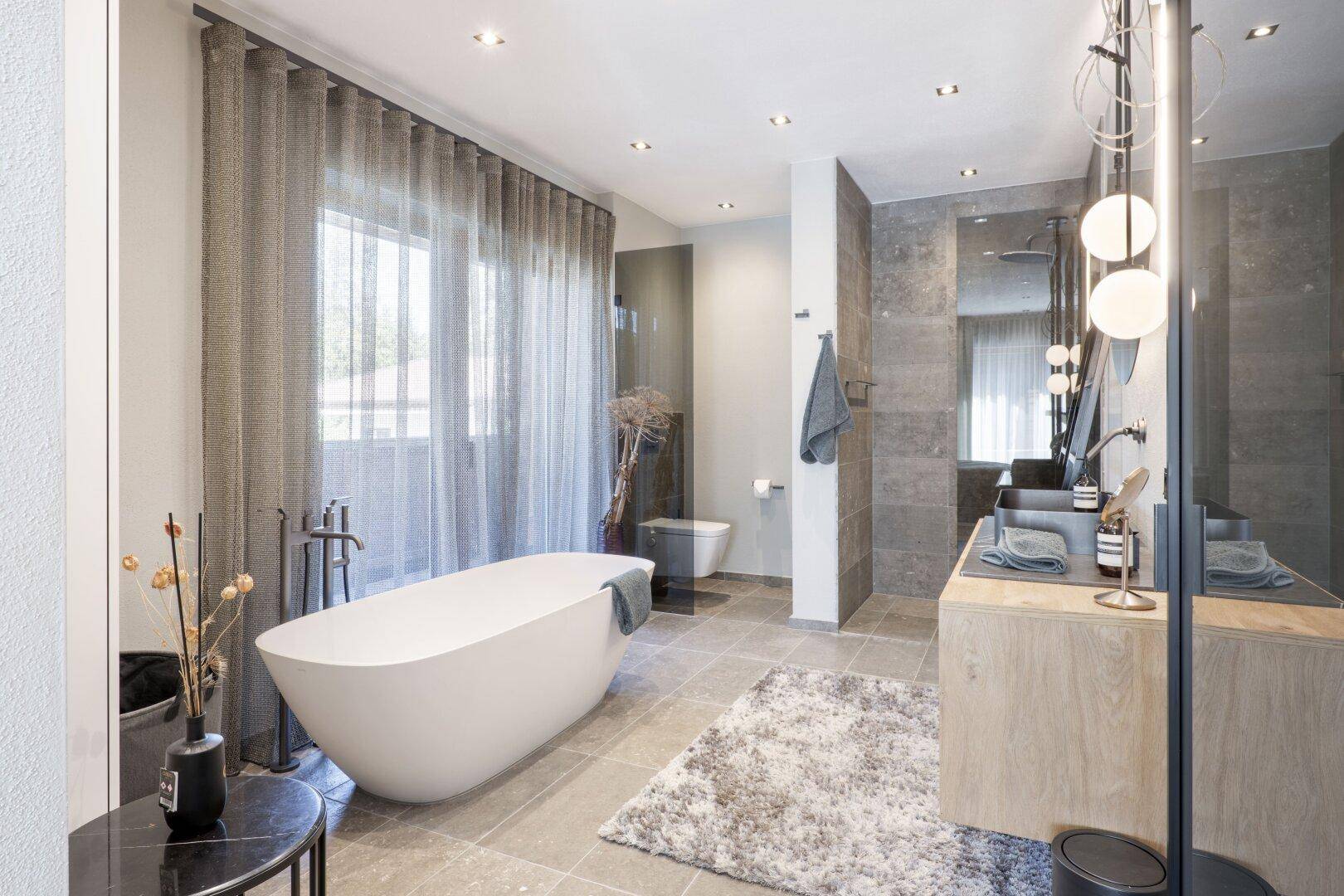 Modernes Badezimmer mit freistehender Badewanne, Doppelwaschbecken und großen Fliesen.