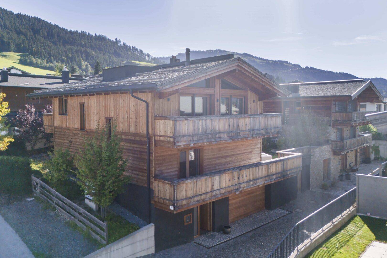 Traditionelles Holzhaus im alpinen Stil mit Balkonen und Bergblick in sonniger Lage.