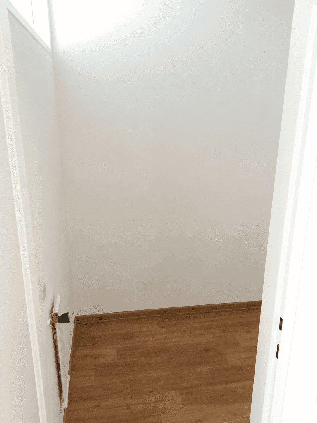 Leerer Abstellraum mit Holzboden und weiß gestrichenen Wänden, ideal für zusätzlichen Stauraum.