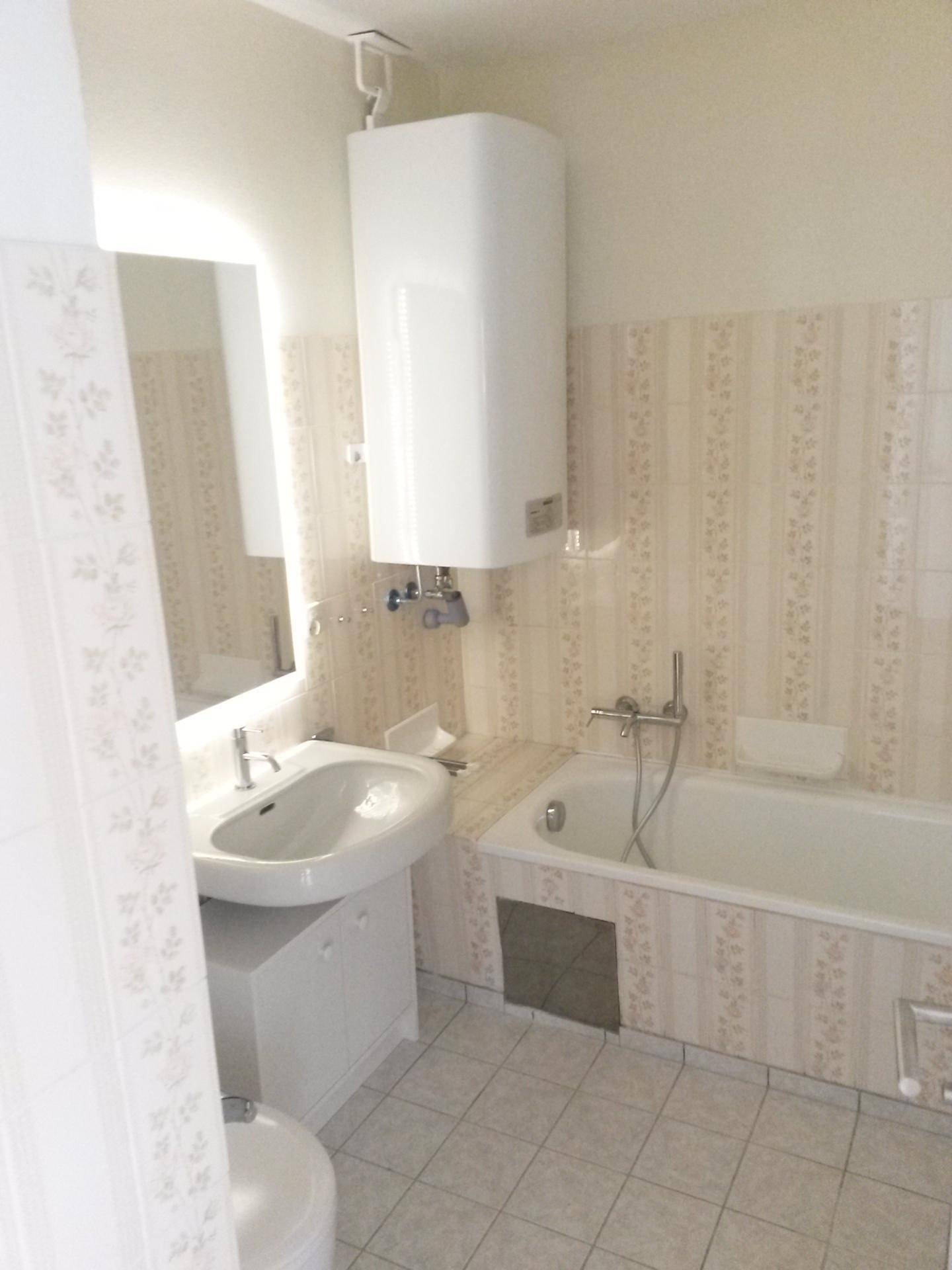 Badezimmer mit Badewanne, Waschbecken und Wandfliesen im klassischen Design.