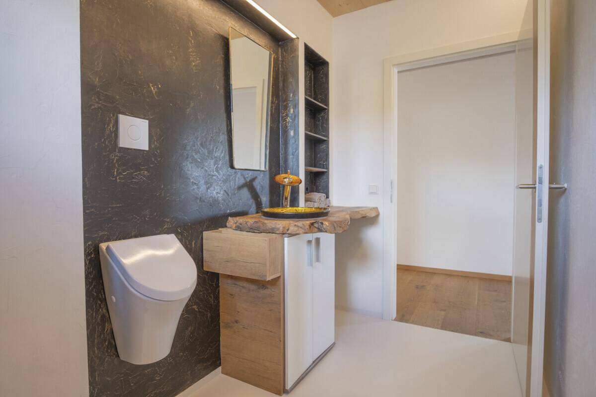 Modernes Gäste-WC mit Urinal, einzigartigem Holzwaschtisch und dunkler Akzentwand.
