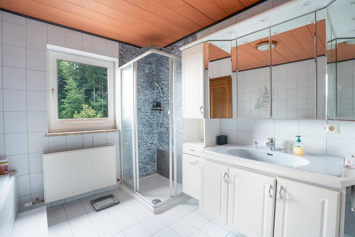 Helles Badezimmer mit Duschkabine, Waschtisch und Spiegelschrank.