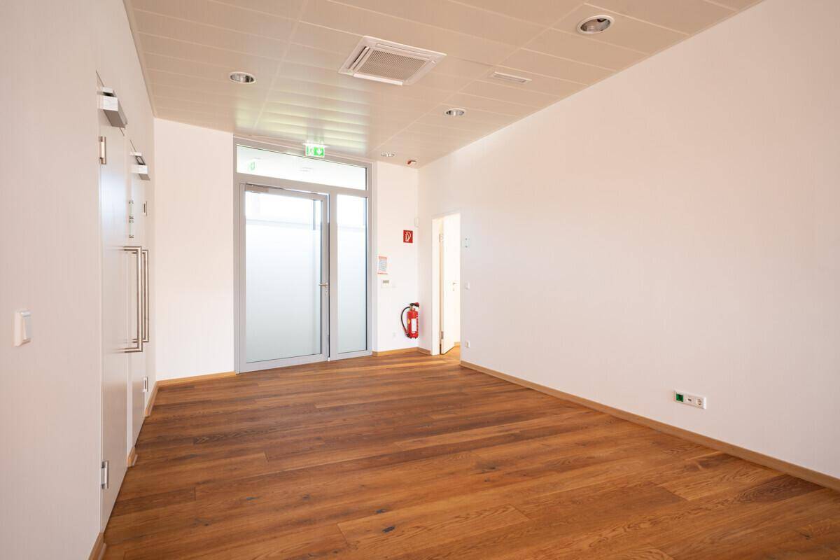 Eingangsbereich mit Holzboden, weiß gestrichenen Wänden und Brandschutzvorrichtungen.