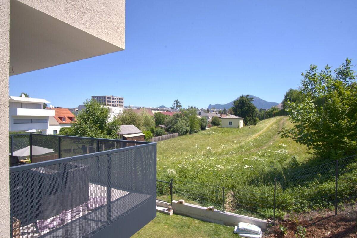 Weitläufiger Blick vom Balkon über grüne Wiesen und die umliegende Landschaft mit Bergen.