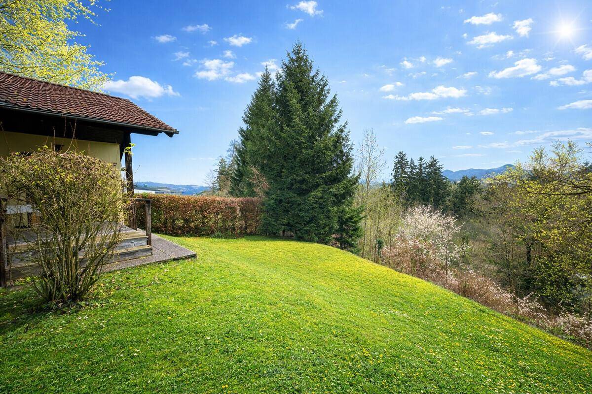 Seitlicher Blick auf das Haus mit abfallendem Garten und weitem Ausblick in die Natur.