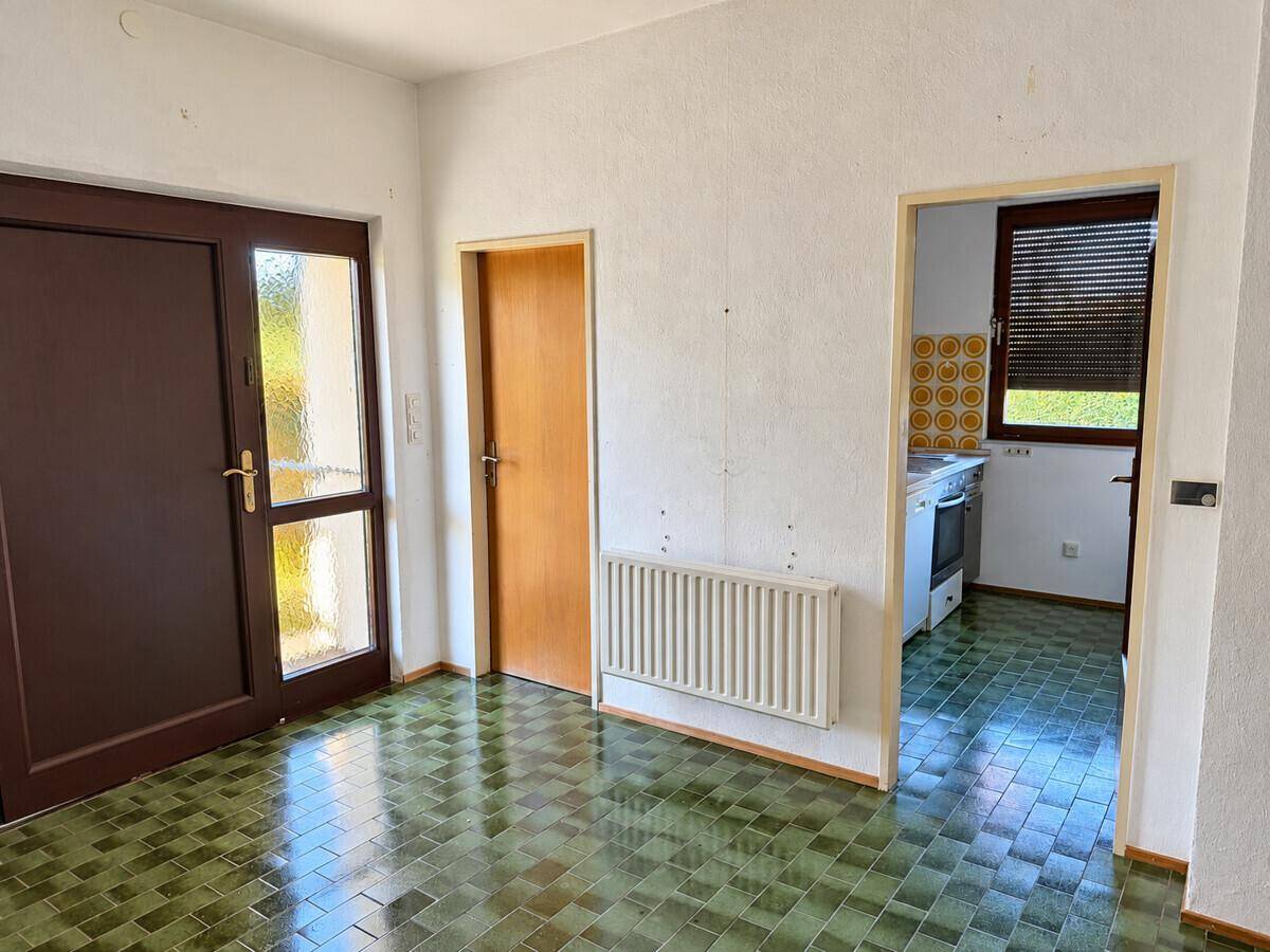 Flur mit gefliestem Boden und Zugang zur Küche sowie zum Außenbereich.
