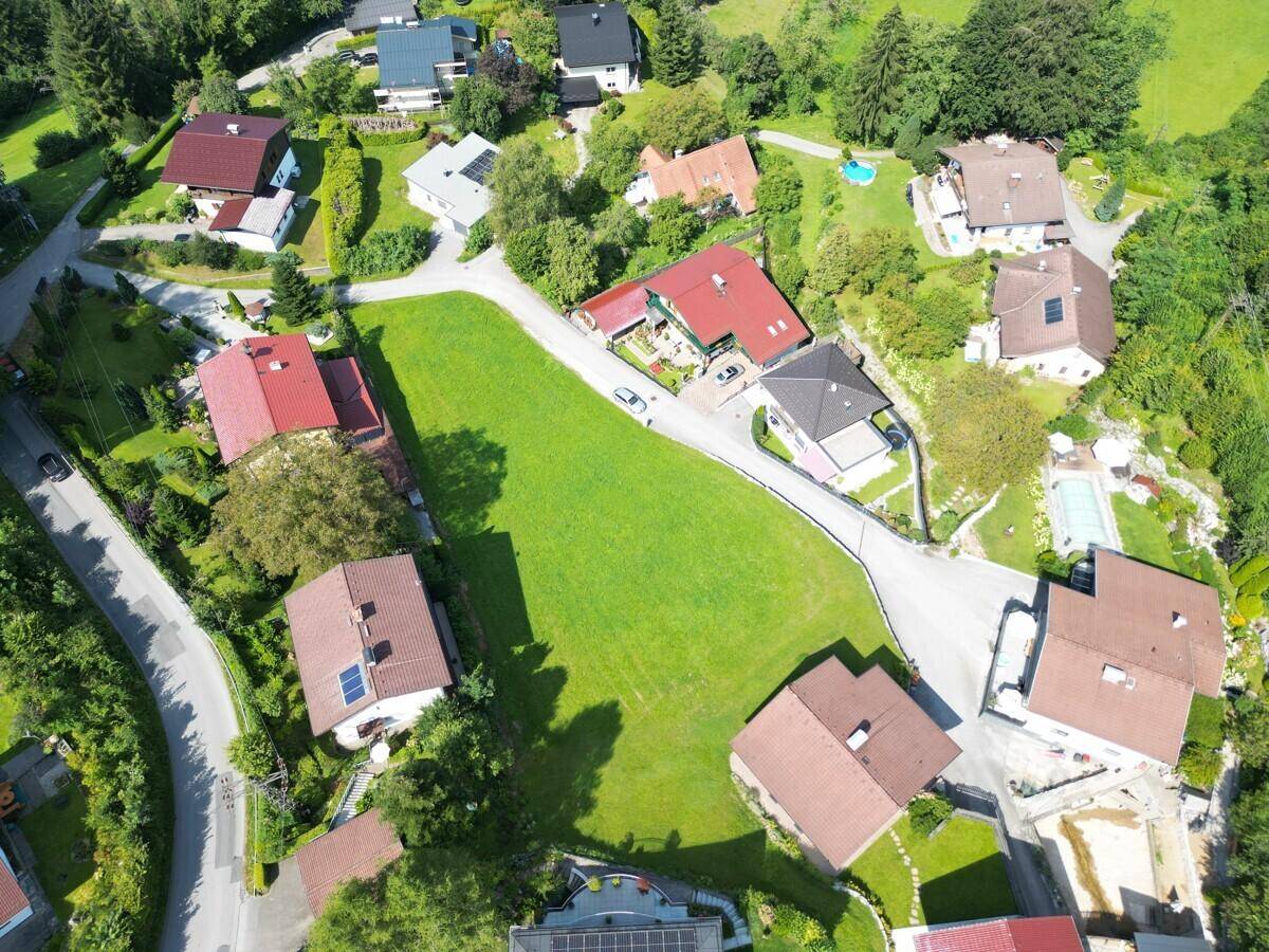 Luftaufnahme einer Wohnsiedlung mit Einfamilienhäusern, Straßen und großen Grünflächen.