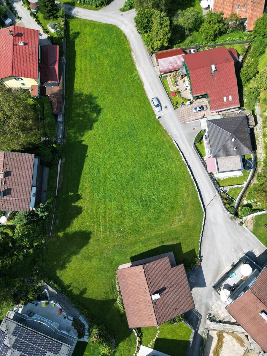 Detaillierte Luftansicht eines großen grünen Grundstücks umgeben von Wohnhäusern und Straßen.