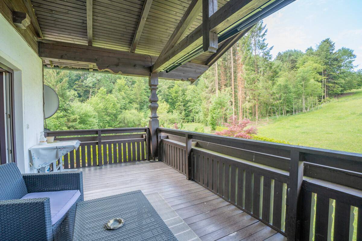Überdachter Balkon mit Sitzgelegenheiten und idyllischem Blick auf den Wald.