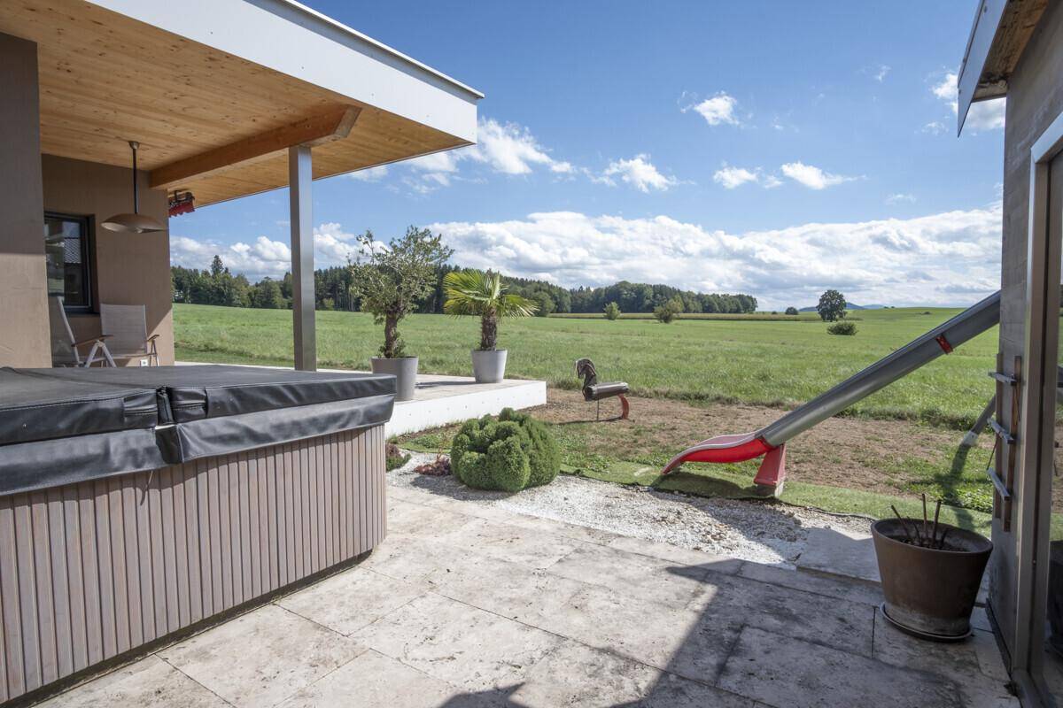 Terrasse mit Whirlpool, Kinderrutsche und weitem Blick auf die grüne Landschaft.