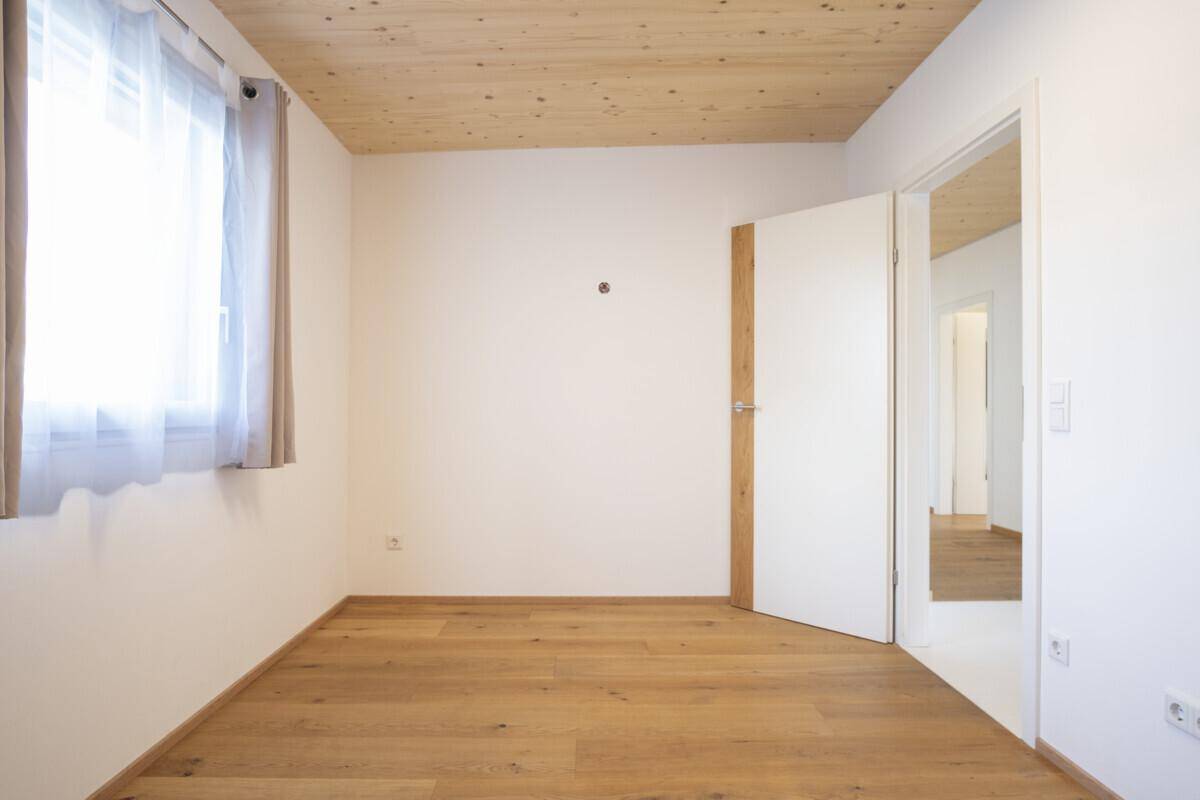 Heller Raum mit Holzboden, Holzdecke und Fenster, ideal als Schlaf- oder Arbeitszimmer.