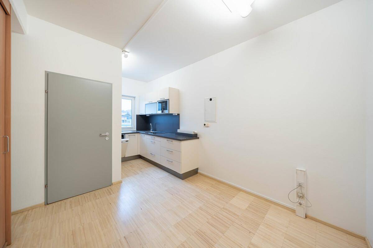 Kleine, funktionale Küchenzeile in einem hellen Raum mit Holzboden und weiß gestrichenen Wänden.