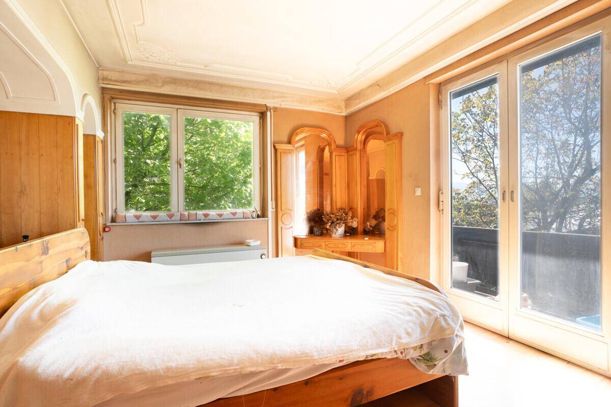 Schlafzimmer mit Holzbett, Stuckdecke und Zugang zu einem Außenbereich.
