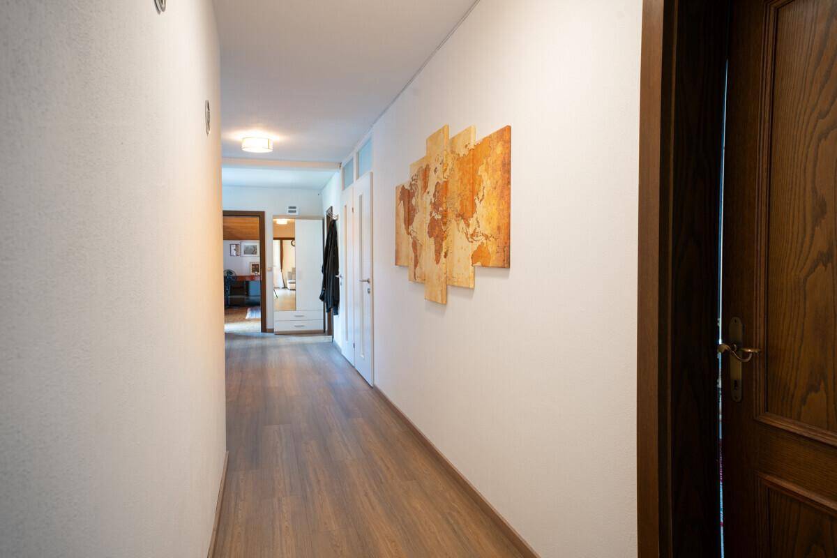 Langer Flur mit Holzfußboden und moderner Wanddekoration.