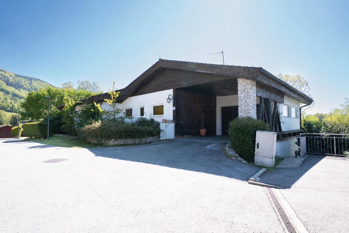 Einfamilienhaus mit Carport und gepflegter Außenanlage in ländlicher Umgebung.