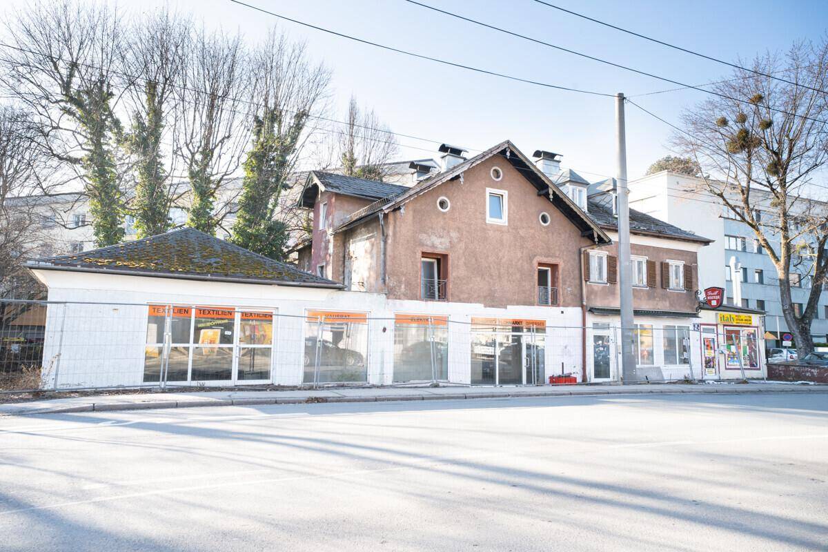 Gebäudeansicht von der Straße mit Ladenflächen im Erdgeschoss und Wohnungen darüber.