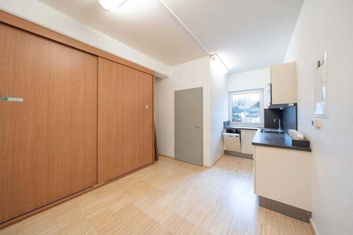 Kompakte Küchenzeile mit integrierten Geräten und großen Holzschiebetüren für Stauraum.