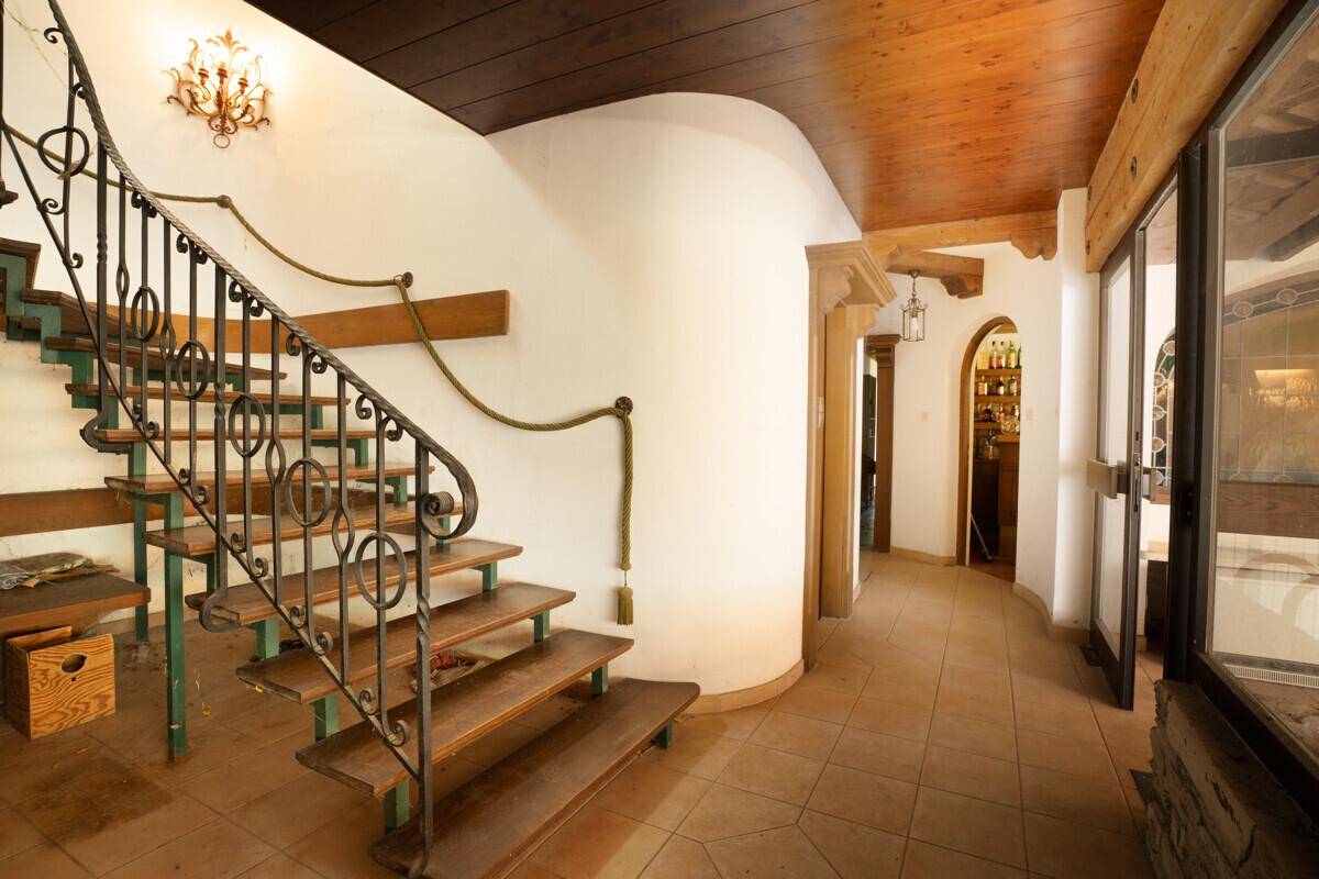 Eingangsbereich mit geschwungener Treppe und Holzbalkendecke.