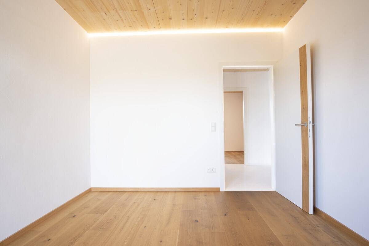 Leerer Raum mit hellem Holzboden und Holzdecke, bereit zur individuellen Gestaltung.