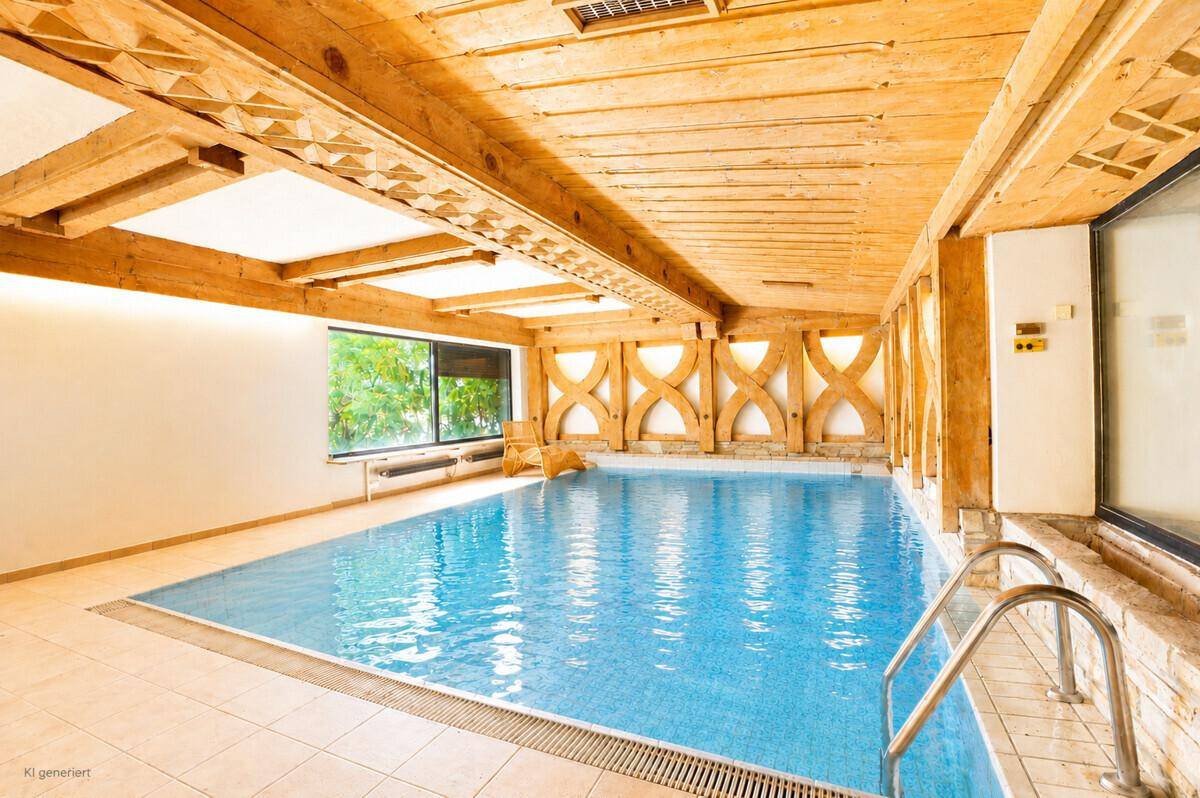 Innenpool mit Holzbalkendecke, großen Fenstern und Fliesenboden.