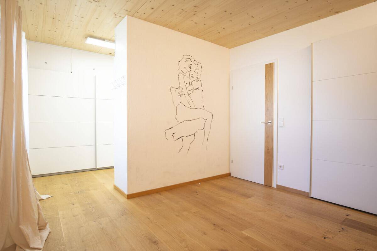 Helles Schlafzimmer mit Holzboden, Holzdecke und integrierten Kleiderschränken.