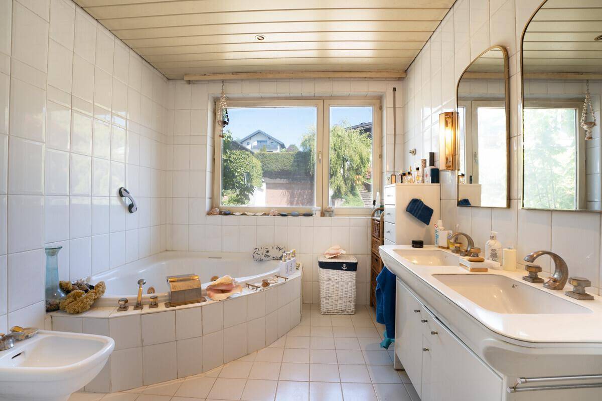 Geräumiges Badezimmer mit Doppelwaschbecken, Badewanne und Fenster.