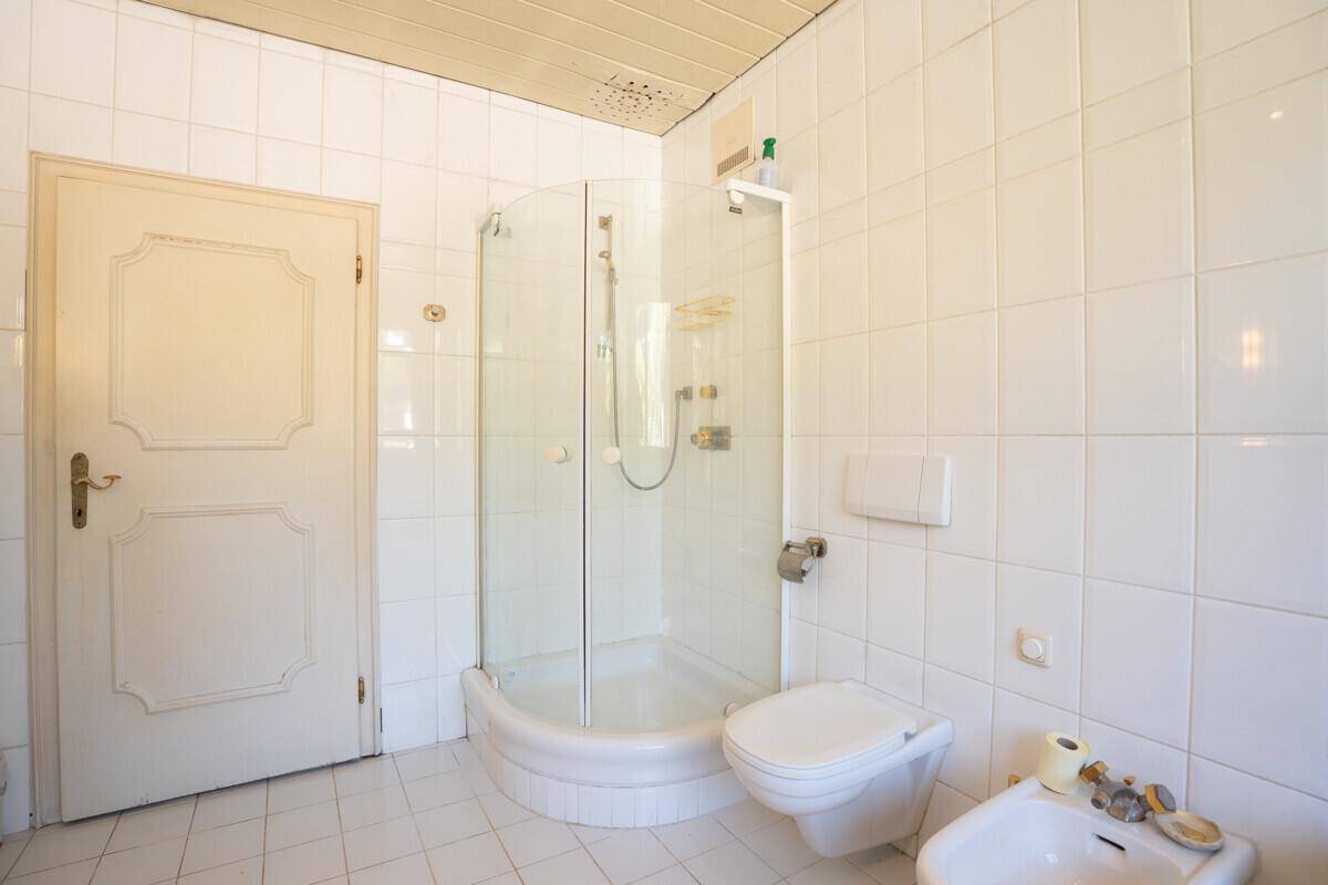 Badezimmer mit Duschkabine, WC und Bidet, komplett gefliest.