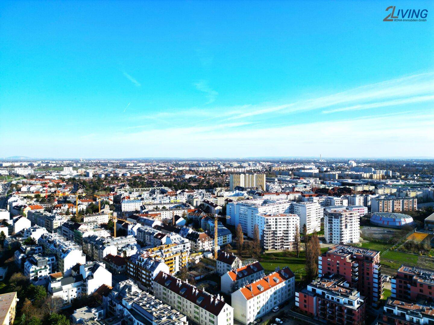 Weitläufiger Panoramablick über die Stadt mit zahlreichen Wohngebäuden unter blauem Himmel.