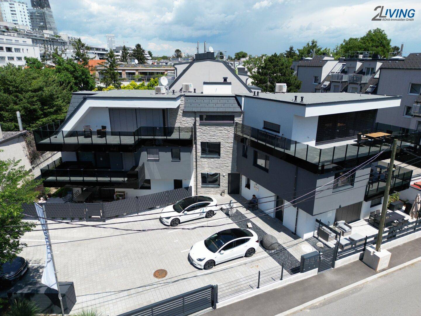 Modernes Mehrfamilienhaus mit Balkonen, Terrassen und Außenparkplätzen.