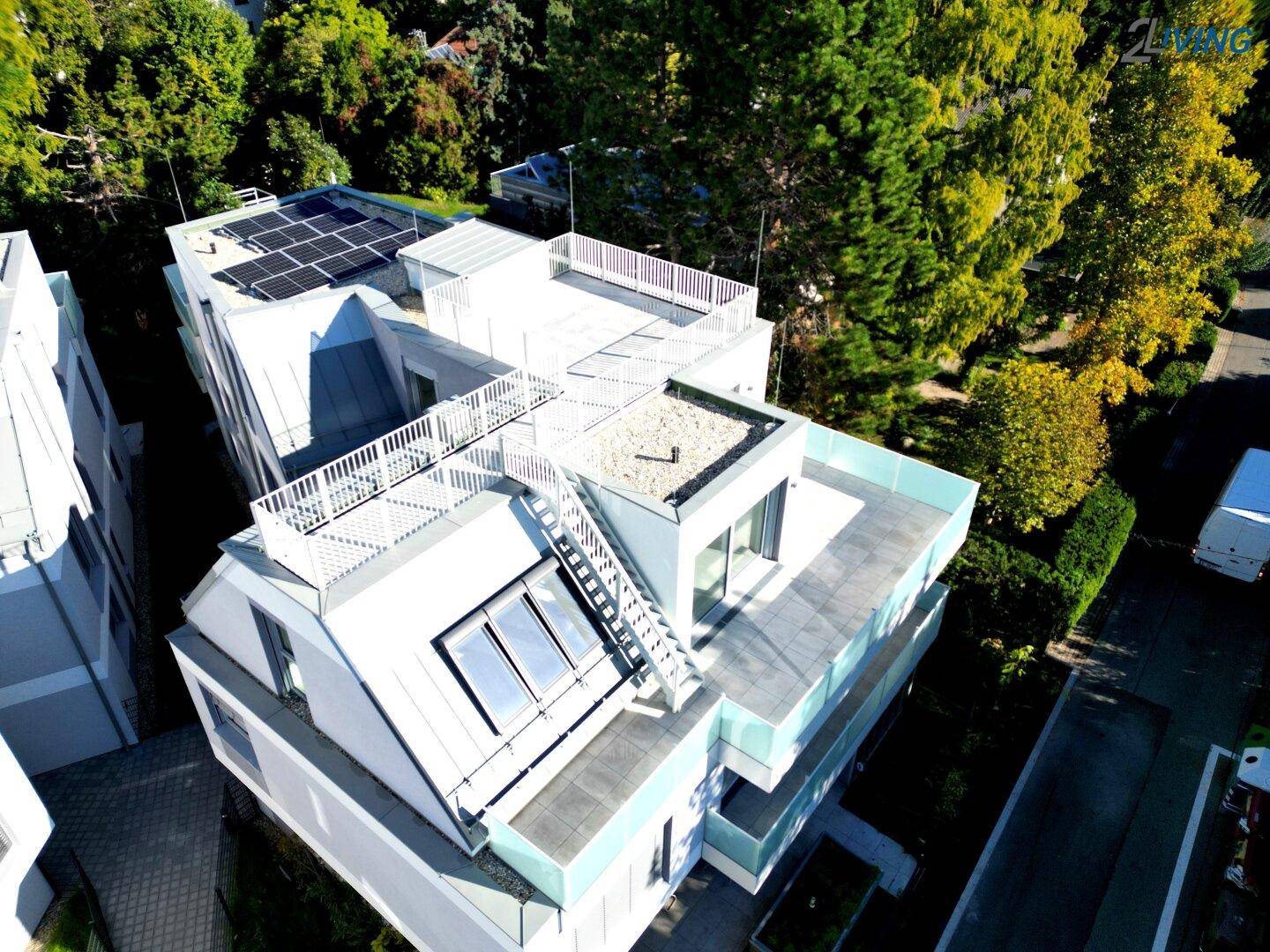 Draufsicht auf ein modernes Wohngebäude mit Dachterrasse und Solarpaneelen auf dem Dach.