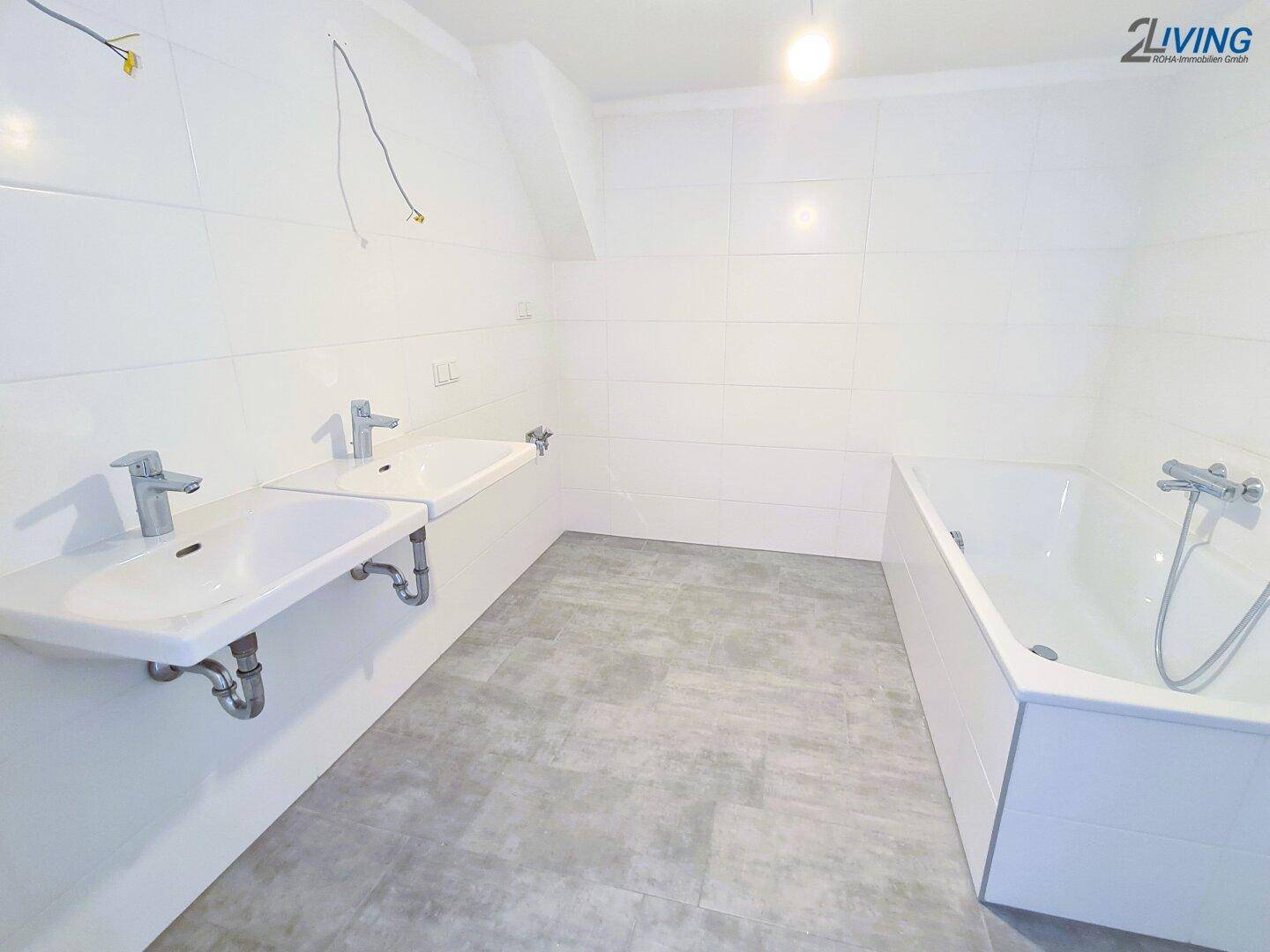 Modernes Badezimmer mit zwei Waschbecken, Badewanne und weißen Fliesen, noch im Ausbau.