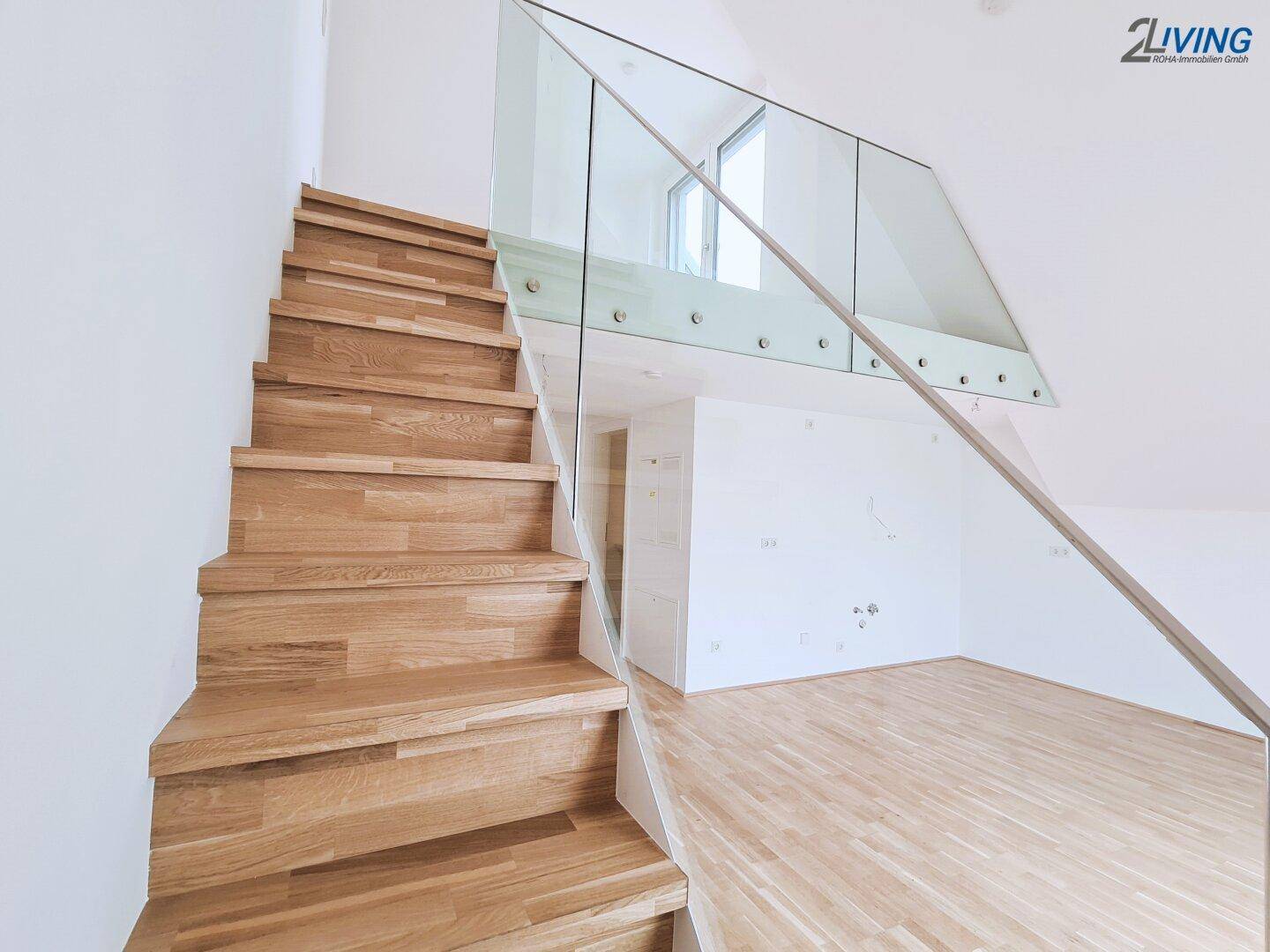 Moderne Holztreppe mit eleganter Glasbrüstung verbindet die Etagen und ergänzt den Holzboden.