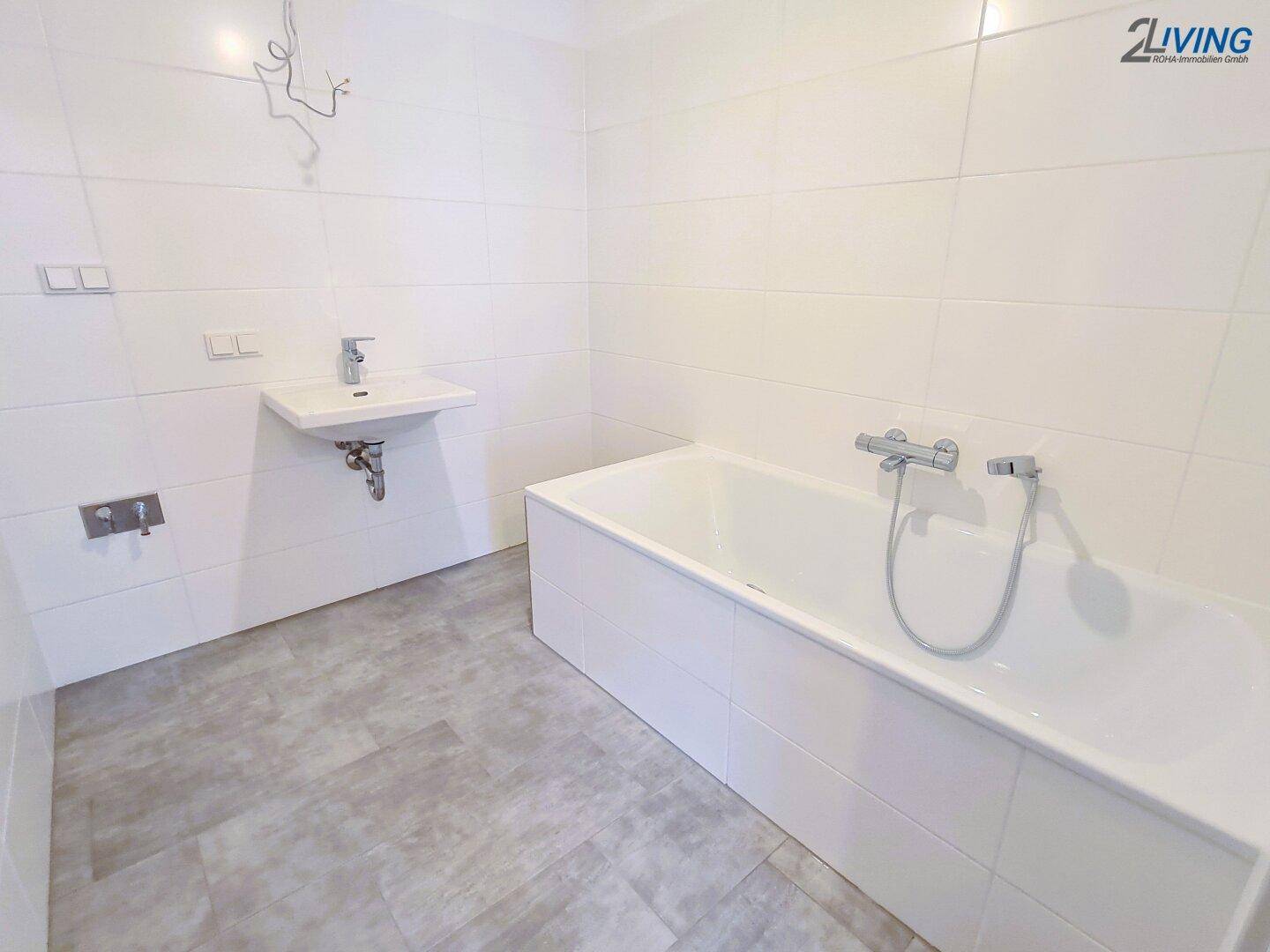 Modernes Badezimmer mit weißen Fliesen, Badewanne und Waschbecken, bereit zur Einrichtung.