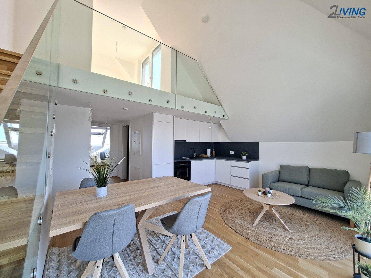 Geräumiger Wohn-Essbereich mit offener Küche, Holzparkett und eleganter Glasbrüstung zur Galerie.
