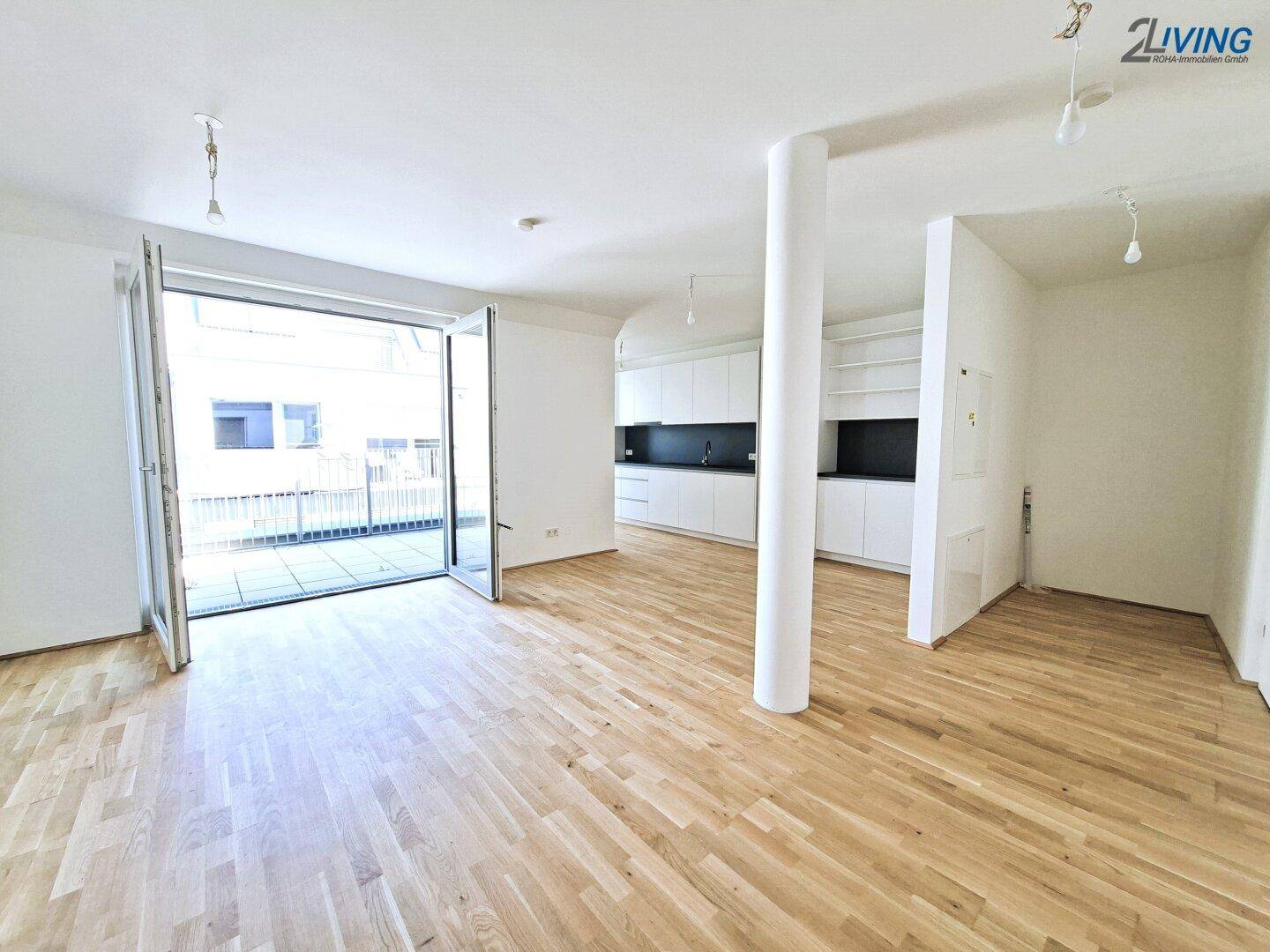 Heller, offener Wohnbereich mit Holzboden und Zugang zu einer großen Terrasse, ideal für modernes Wohnen.