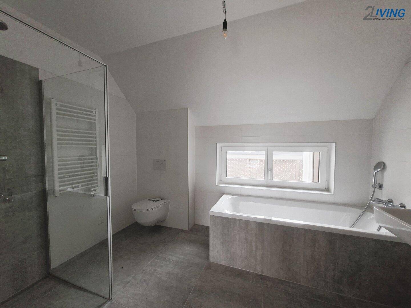 Modernes Badezimmer mit begehbarer Dusche, Badewanne und Wand-WC unter einer Dachschräge.