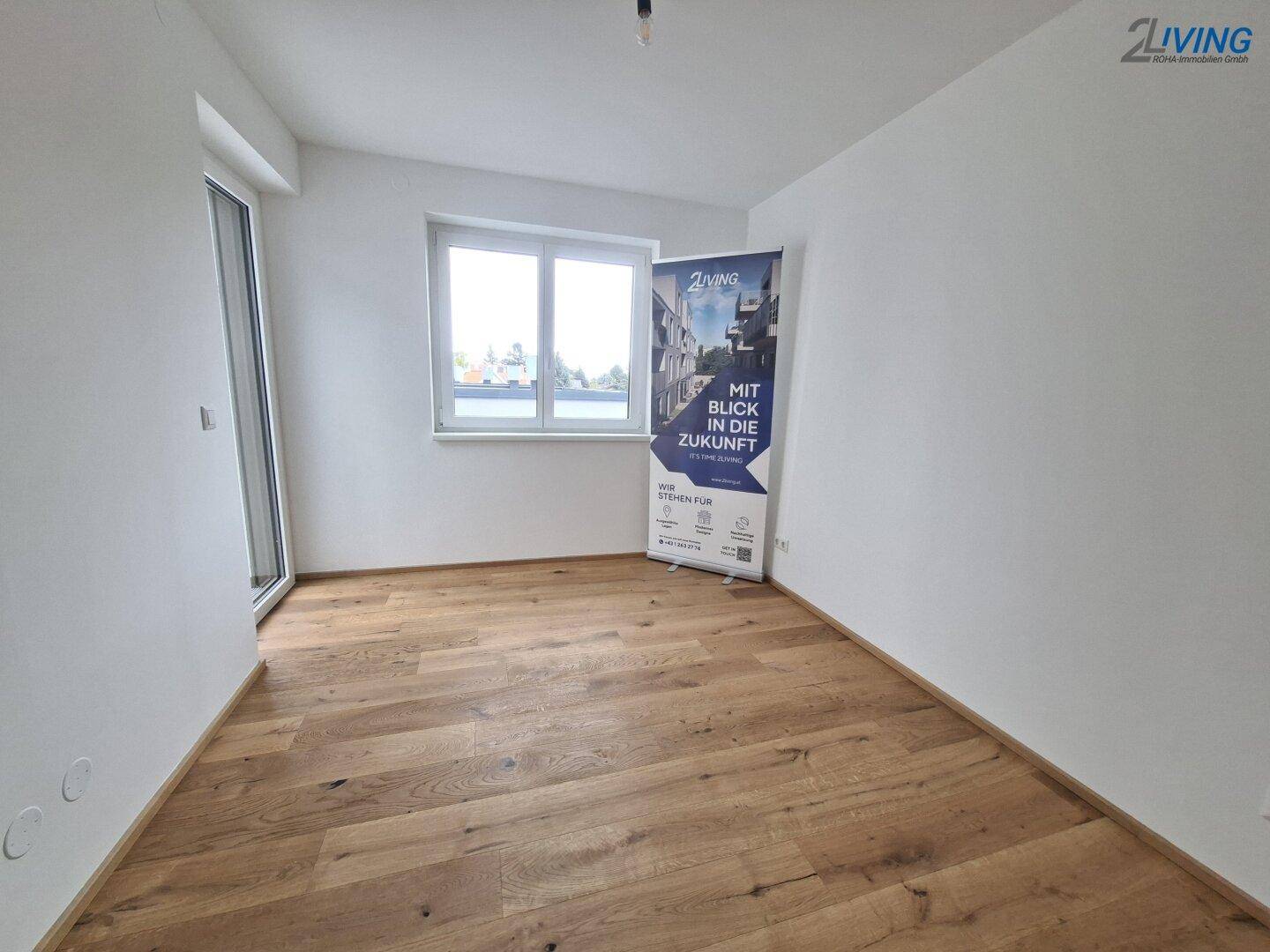 Helles Zimmer mit Parkettboden und großem Fenster, ideal als Schlaf- oder Arbeitszimmer.